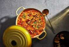 an overhead view of a casserole dish with clams in it and a yellow pot next to it