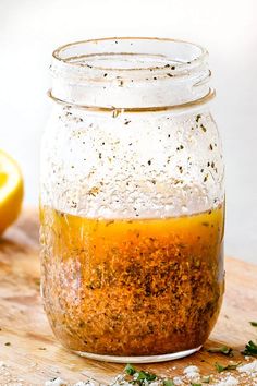 a glass jar filled with seasoning sitting on top of a wooden cutting board next to a lemon