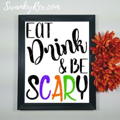 an orange flower sitting next to a black framed sign that says eat drink and be scary