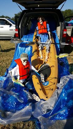 there is a skeleton sitting in the back of a kayak with two life vests on