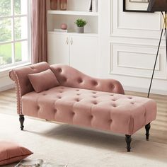 a pink chaise lounger sitting on top of a wooden floor next to a window