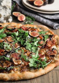 a close up of a pizza on a table with figs and other food items