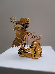 a gold sculpture is sitting on top of a white table and it looks like christmas decorations