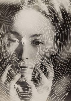 a woman holding her face in front of a spider web