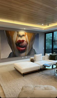 a living room filled with furniture and a large painting on the wall above it's windows