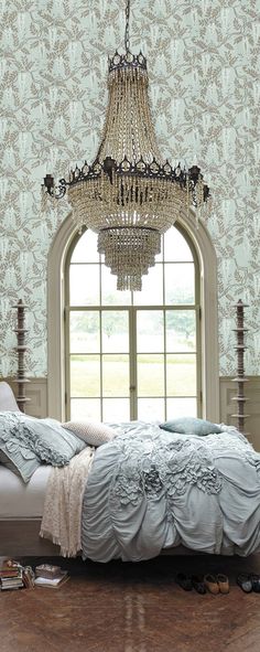 a bedroom with a bed and chandelier hanging from the ceiling