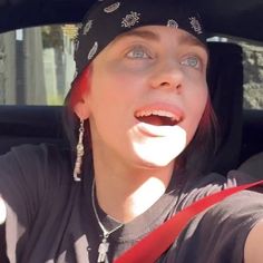 a woman wearing a bandana and sticking her tongue out in the back seat of a car