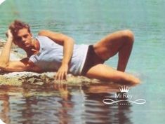 a woman laying on top of a rock in the water with her legs spread out