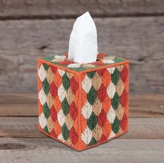 an orange and green checkered tissue dispenser sitting on a wooden table