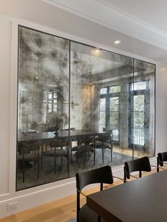 a dining room table and chairs in front of a glass wall