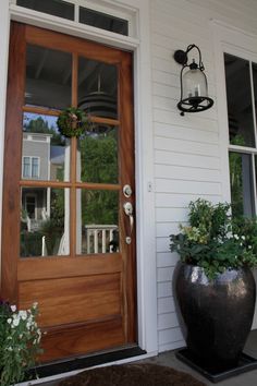 two large planters on the outside of a house with a wooden door and window