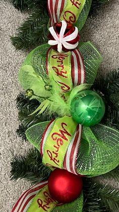 a christmas wreath with green and red ribbons