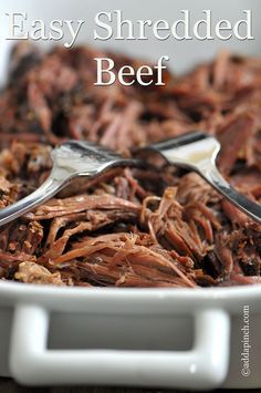 shredded beef in a white bowl with two spoons resting on the side and text overlay that reads easy shredded beef