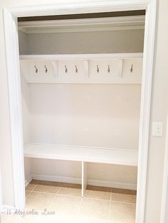 an empty white closet with several coat hooks