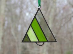 a stained glass hanging ornament in the shape of a triangle with green stripes