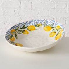 a blue and white bowl with lemons painted on the side, sitting on a table