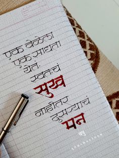 a person writing on a piece of paper with a pen in their hand and the words written in two different languages