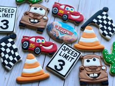 cookies decorated to look like cars and hats are laid out on a white wooden surface