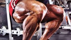 a man squatting down on a bench in a gym with his legs bent forward