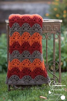 a crocheted blanket sitting on top of a metal stand next to a planter