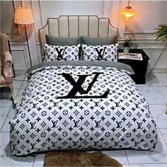 a bed covered in black and white louis vuitton print with two pillows on it