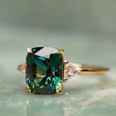 a green and white diamond ring sitting on top of a table