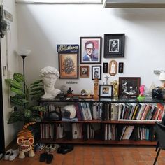 a bookshelf filled with lots of books next to a wall covered in pictures