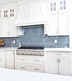 a kitchen with white cabinets and blue backsplash tiles on the countertops,