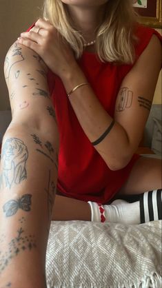 a woman sitting on top of a bed with tattoos on her arms and leggings