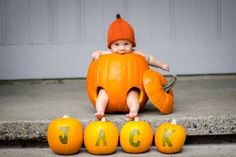 a baby in a pumpkin costume sitting on some jack - o'- lantern letters