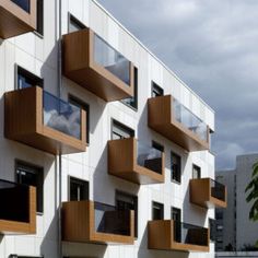 a white building with wooden balconies on the side and windows above it, against a cloudy sky