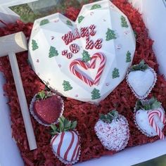 a box filled with assorted chocolate covered strawberries and candy canes in the shape of a heart