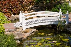 a white bridge over a small pond with lily pads