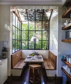 a kitchen with a table and benches in front of a window that looks out onto the garden