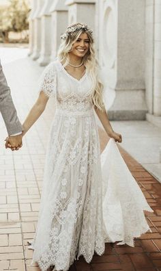 a bride and groom walking down the street holding hands