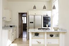 a kitchen with white cabinets and an island in front of the stove top oven is shown