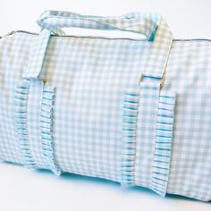 a blue and white checkered duffel bag sitting on top of a white table