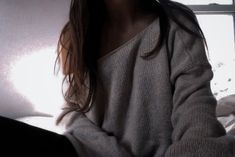 a woman sitting on a bed in front of a window