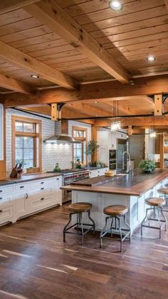 a large kitchen with wooden floors and white cabinets, along with lots of counter space