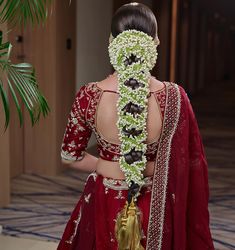 the back of a woman's head is adorned with white and green garlands