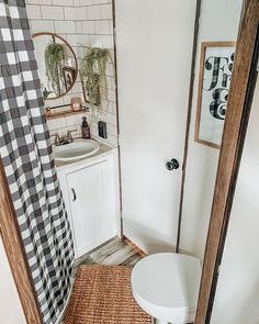 a white toilet sitting next to a sink in a bathroom under a mirror on top of a wooden door