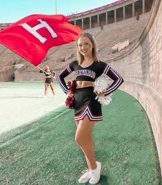 the cheerleader is posing with her pom poms in front of an empty stadium