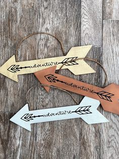 three wooden arrows with the words adventure and adventure written on them sitting on a wood floor