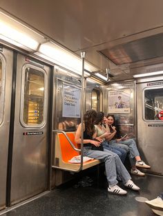 three women sitting on a subway train next to each other