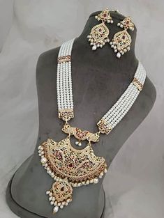 "Incredible timeless ensemble rendered into sophistication to compliment any occasion! Check our Gold Plated Hyderabadi Navratan / Multicolor Jadao Jadau Traditional Necklace set encrusted with multicolor /Navratan colored lab created semi precious  stones with layers of Hyderabadi pearls. Necklace is finished with pearl drops & cluster pearls. Matching earrings makes this set a masterpiece in itself. 👉🏻Approximate necklace length is 30-32\" long adjusted via drawstring. 👉🏻Matching statement Jadau Three Piece Necklace Bridal, White Hand-set Temple Jewelry Sets, Hand Set White Pearl Chandbali Necklace, White Beaded Chandbali Jewelry, Elegant White Chandbali Temple Necklace, White Temple Necklace With Intricate Design For Festivals, White Temple Necklace With Stone Work For Wedding, Bollywood Style Round White Bridal Necklace, Bollywood Style White Round Bridal Necklace