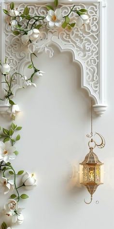 an ornate white wall with flowers and a lantern hanging from it's side on the wall