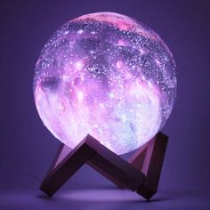 the moon lamp is sitting on top of a wooden stand with purple and blue stars