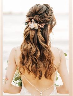 the back of a woman's head with long hair and flowers in her hair