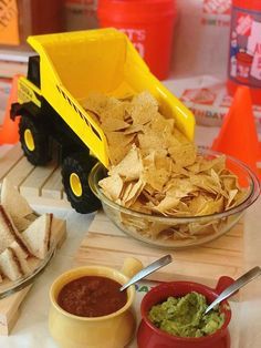 a table topped with bowls filled with chips and guacamole next to a plate of tortilla chips