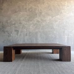 a wooden table sitting on top of a carpeted floor next to a gray wall